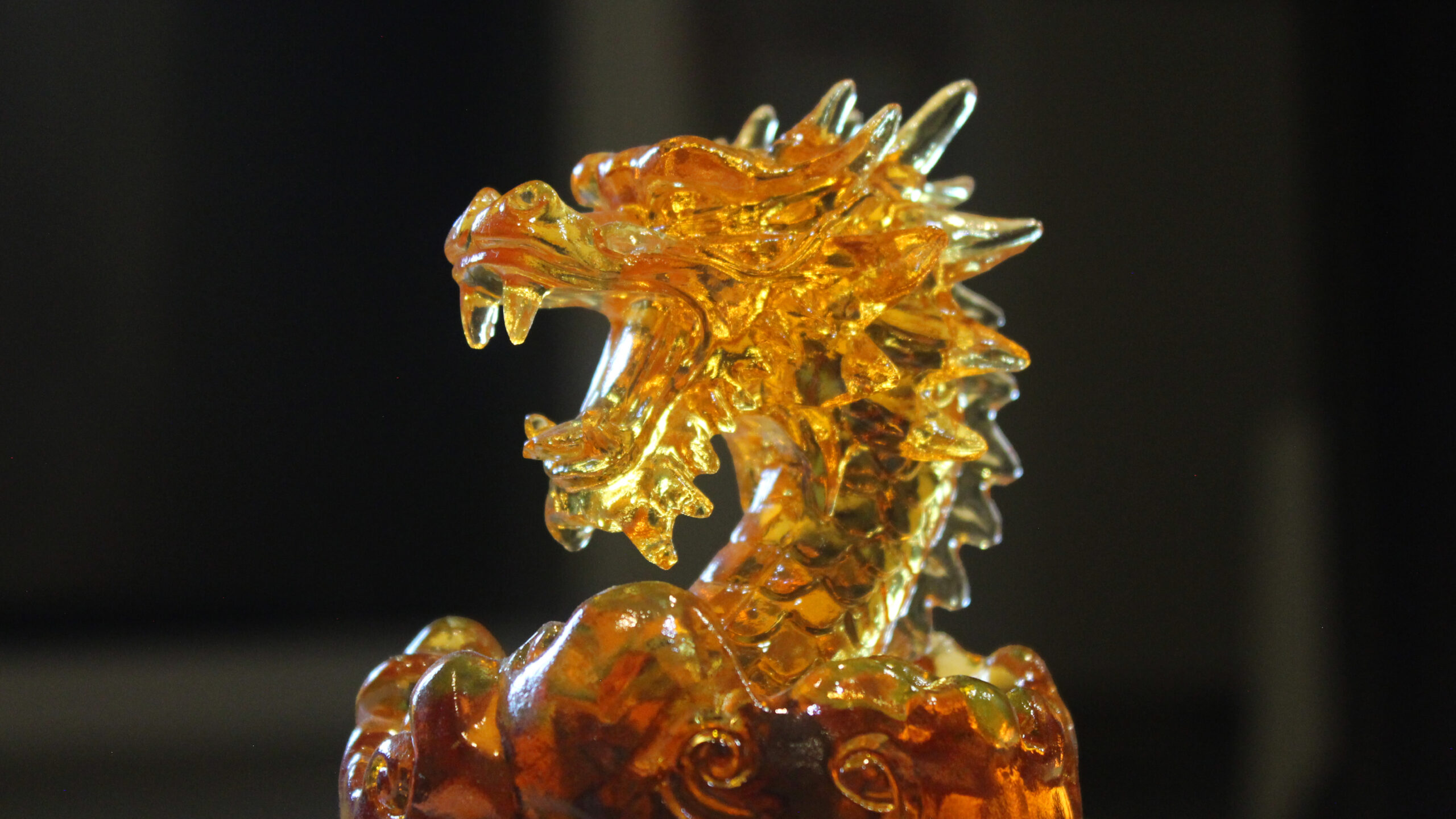 八鎮酒龍首紀念酒瓶蓋特寫，展現精緻琥珀色透光琉璃龍首工藝
