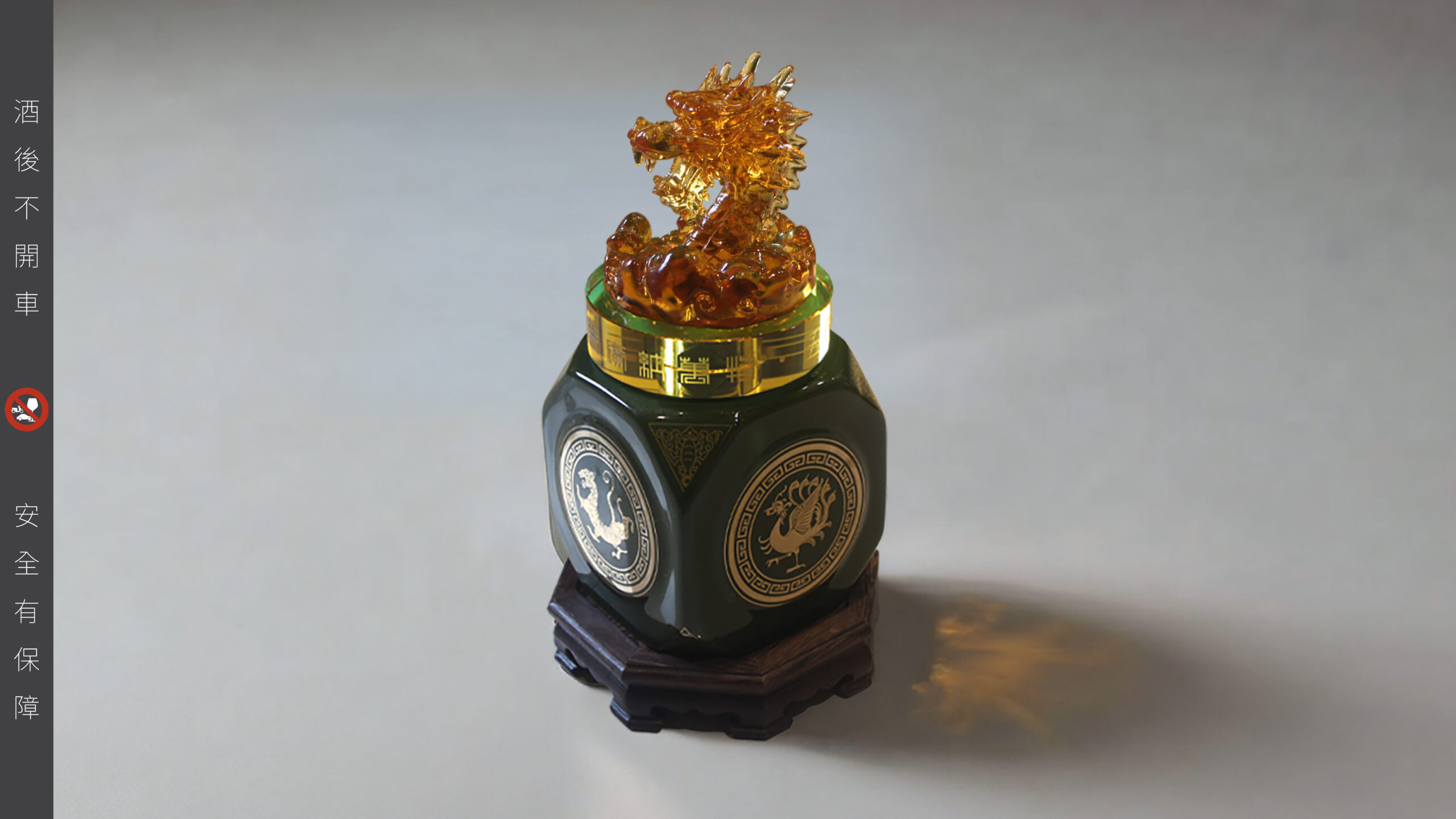 八鎮酒龍首紀念酒造型酒瓶，琥珀色琉璃龍首搭配墨綠陶器與木質底座